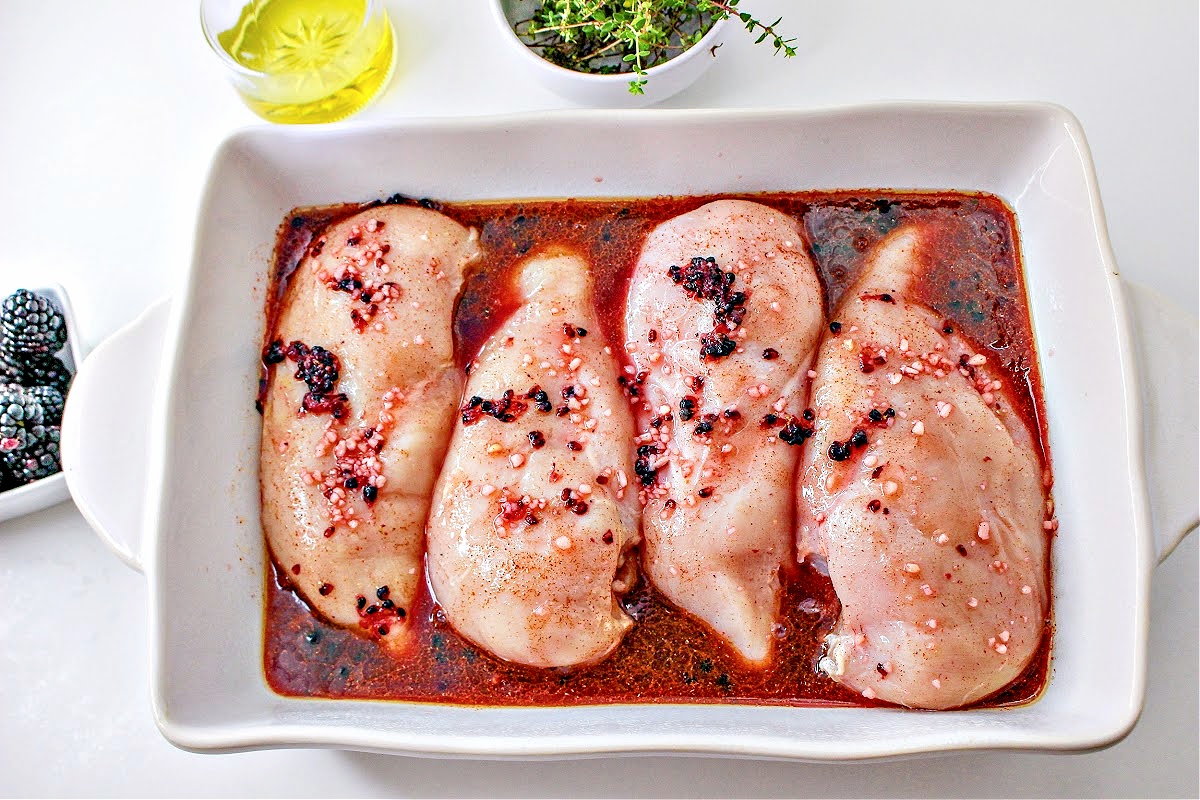 Seasoned raw chicken breasts in a white casserole dish