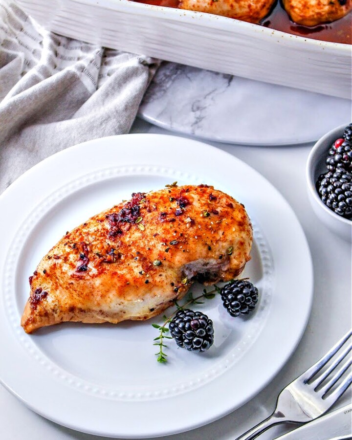A white plate with Keto Blackberry Chicken and 2 blackberries