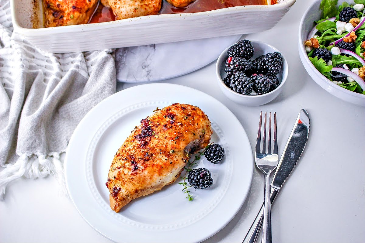 A serving of keto blackberry chicken with a bowl of blackberries and a blackberry arugula salad