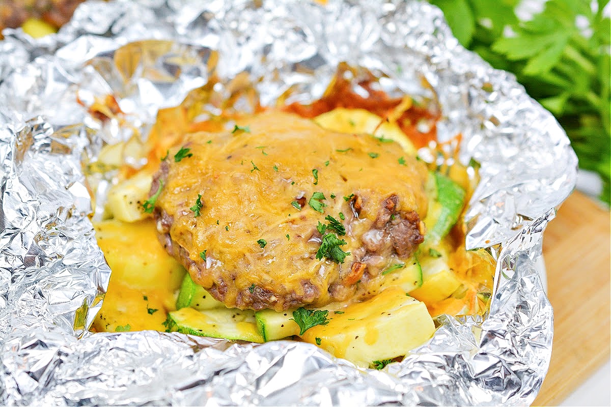 A keto cheeseburger in a foil packet with zucchini and yellow squash