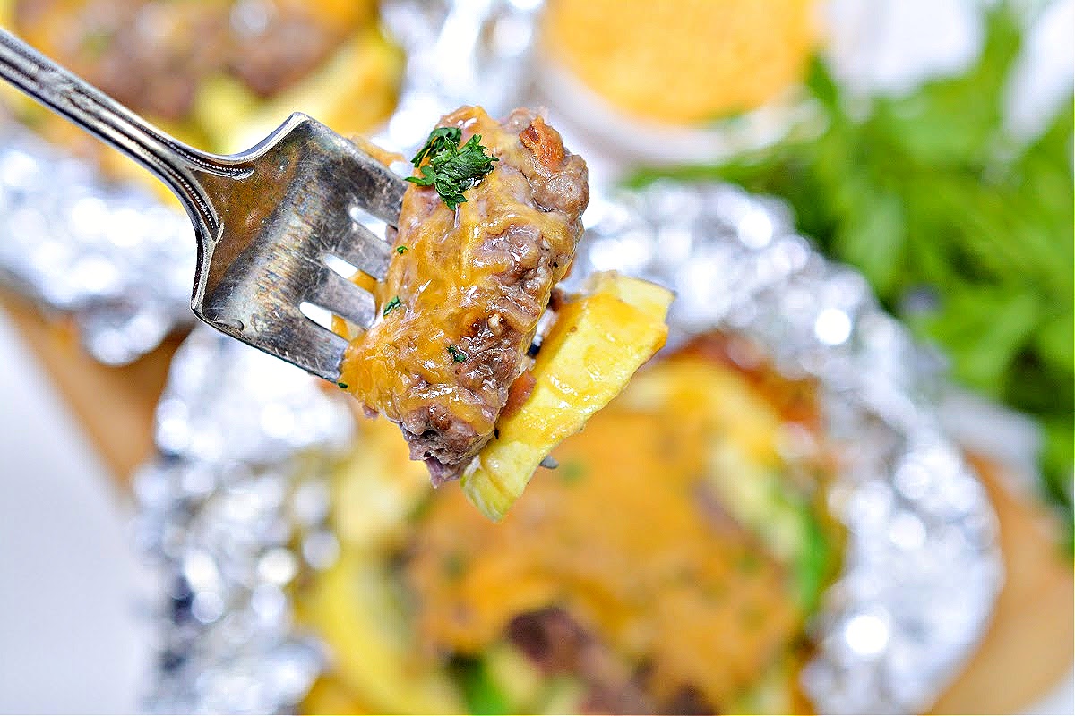 A fork with a bite of keto cheeseburger and yellow squash