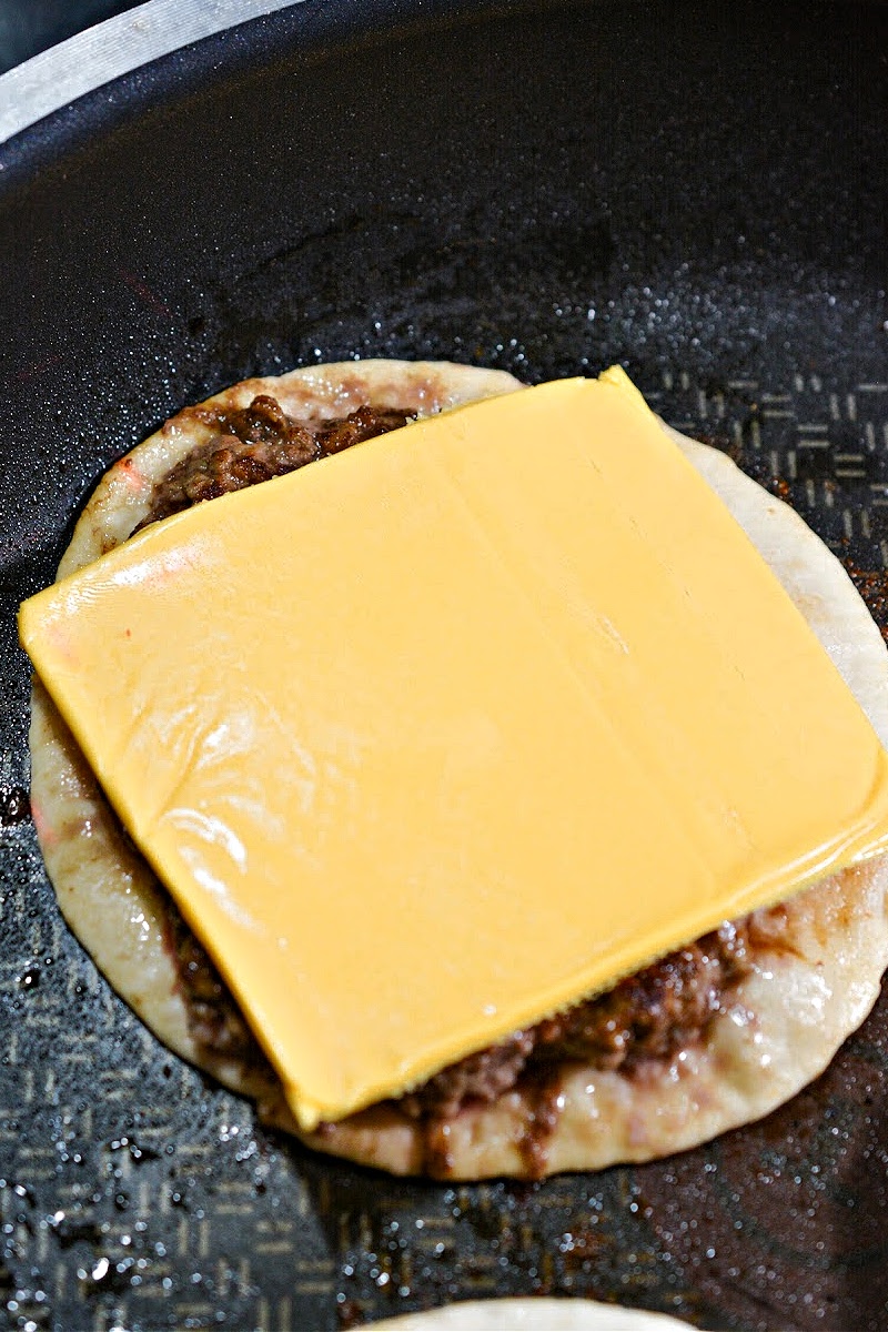 A burger with a slice of American cheese on it