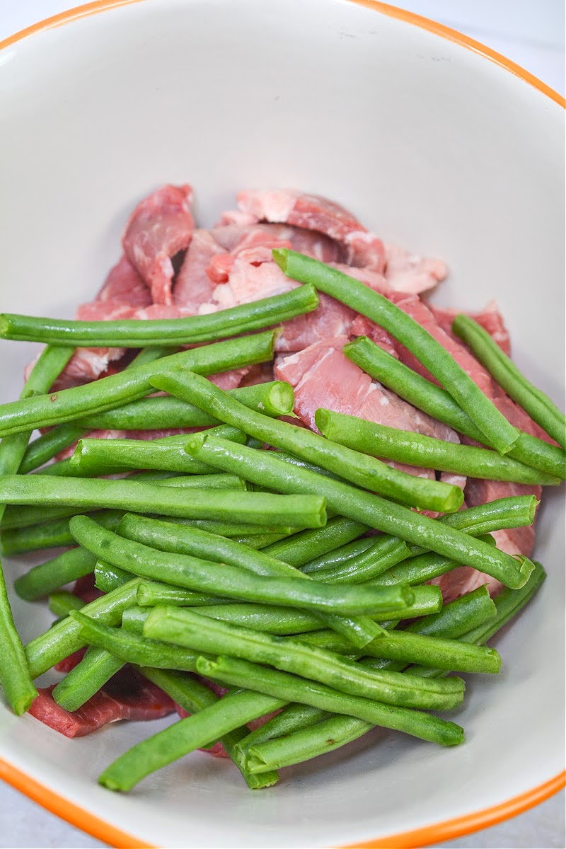 Mixing Green Beans with Strips of Raw Steak