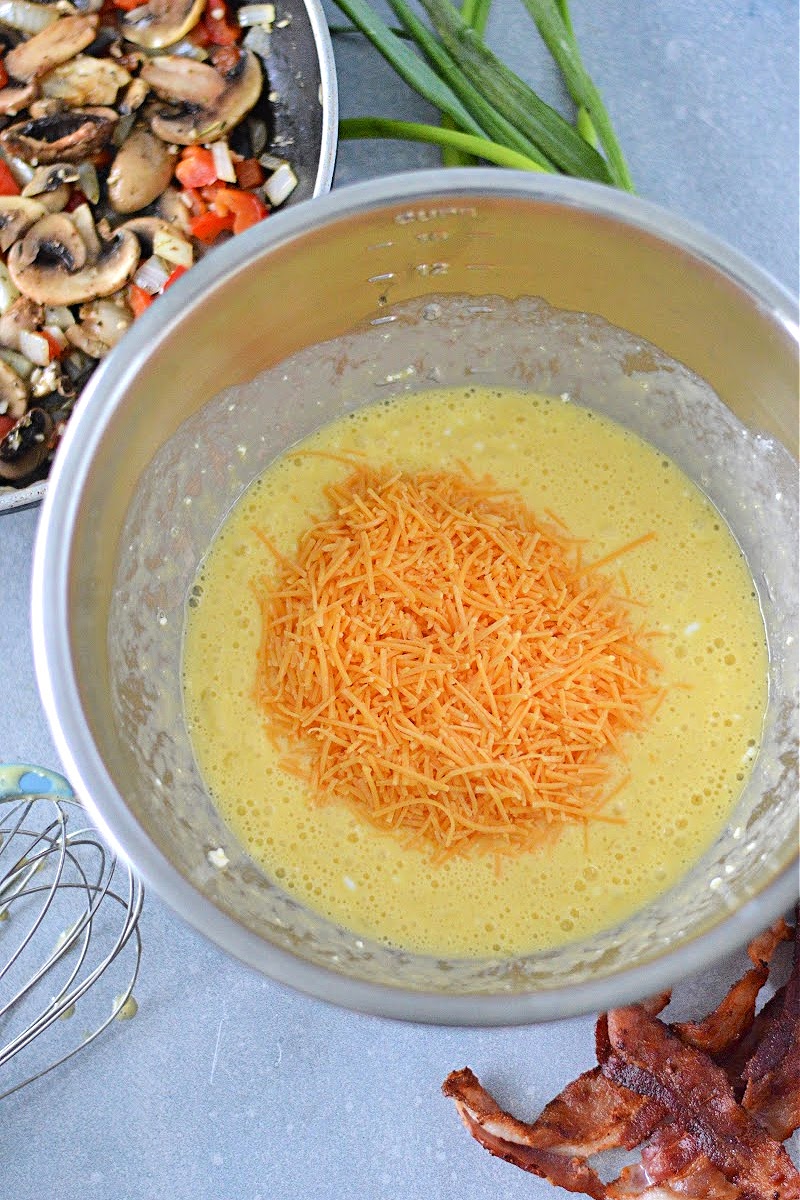 Mixing eggs, cottage cheese, and cheddar cheese in a bowl.