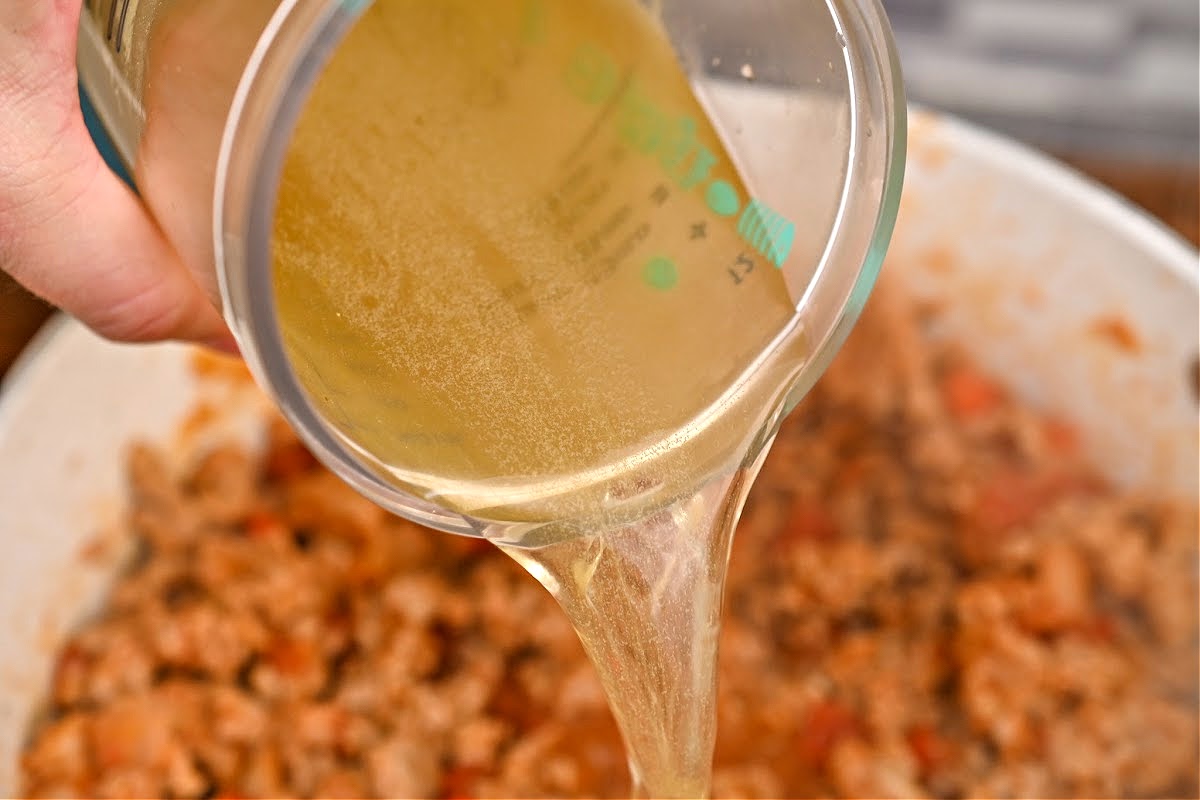 Pouring chicken broth into the chili