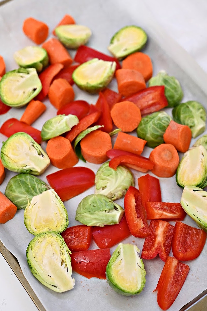 Chopped Red bell peppers, carrots, and brussels sprouts on a sheet pan