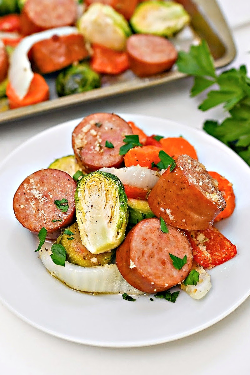 Low Carb Honey Garlic Sausage and Veggies on a white plate in front of a sheet pan of food.