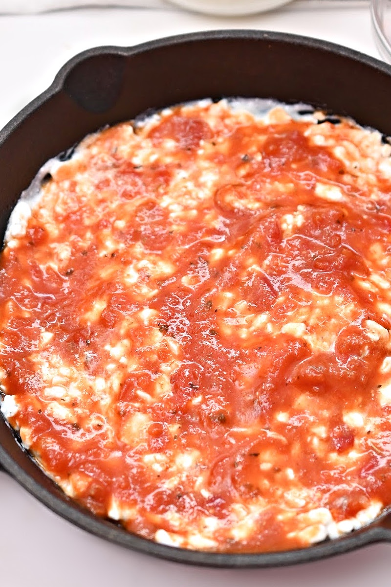 Spreading pizza sauce on the cottage cheese