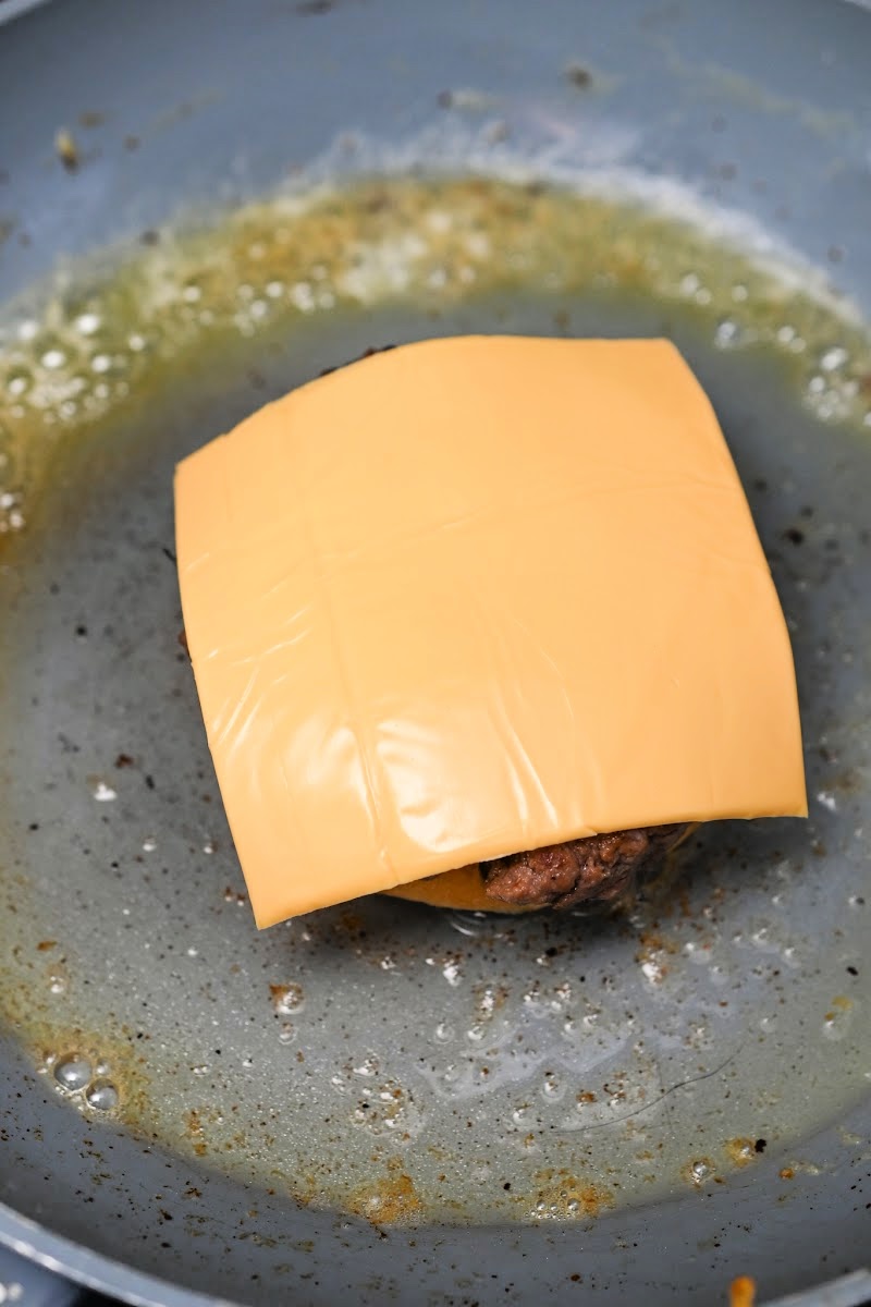 Placing cheese on top of the burger patty