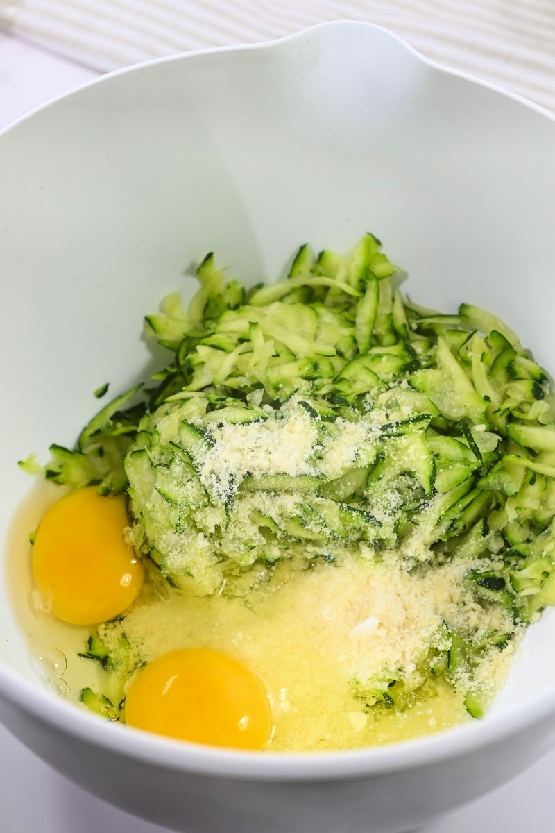 Mixing zucchini and eggs and parmesan cheese in a bowl