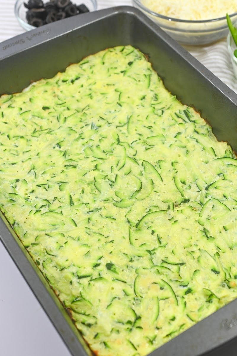 Pressing zucchini mixture to the bottom of the casserole dish