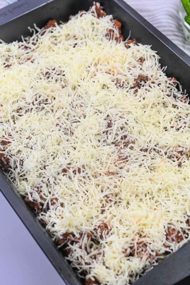 Adding shredded cheese to the casserole