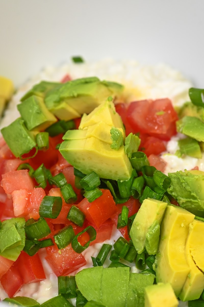 Adding tomatoes and avocado to the dip