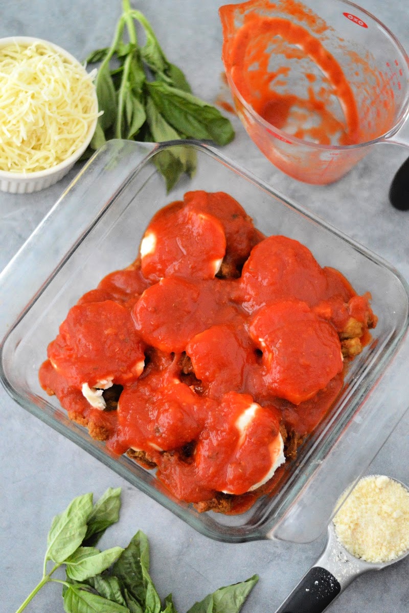 Adding tomato sauce on top of the mozzarella cheese