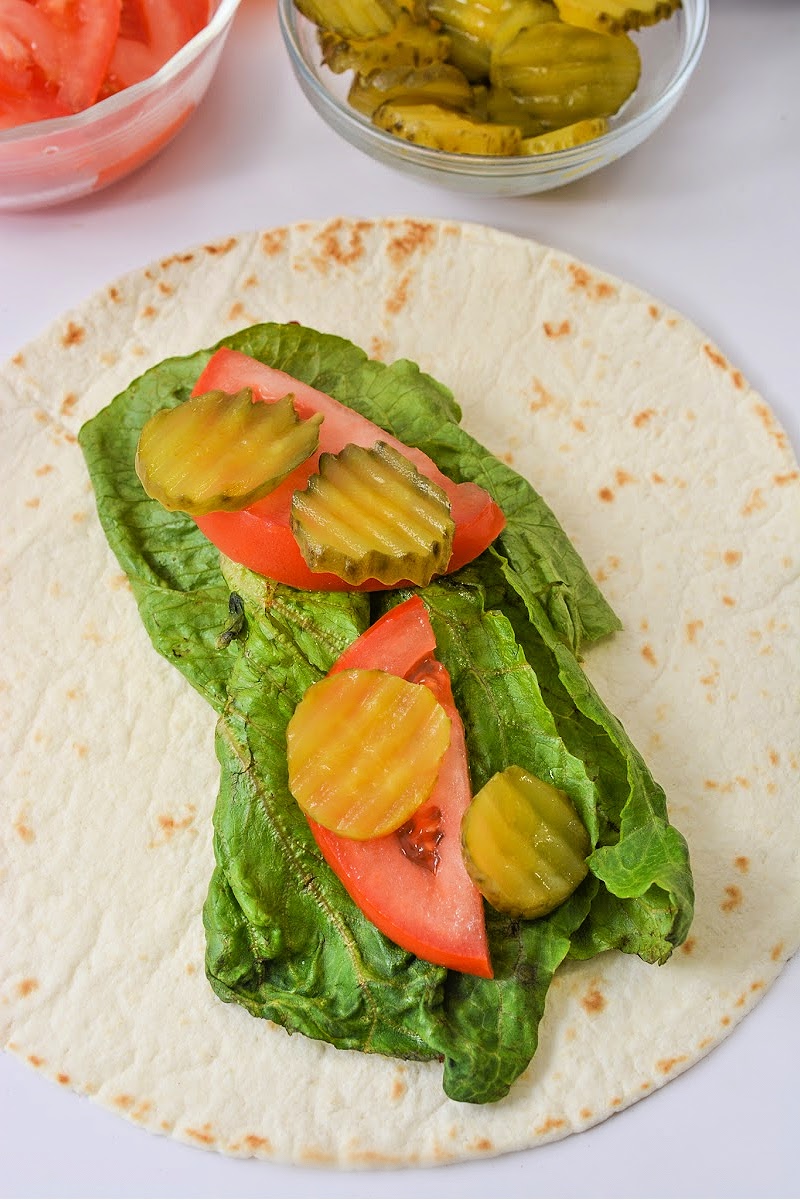 Adding pickles on top of tomatoes and lettuce