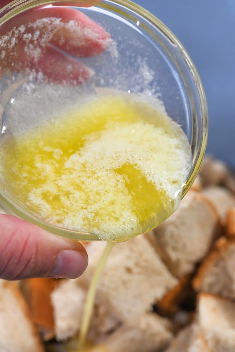 Pouring melted butter on top of the chopped bread