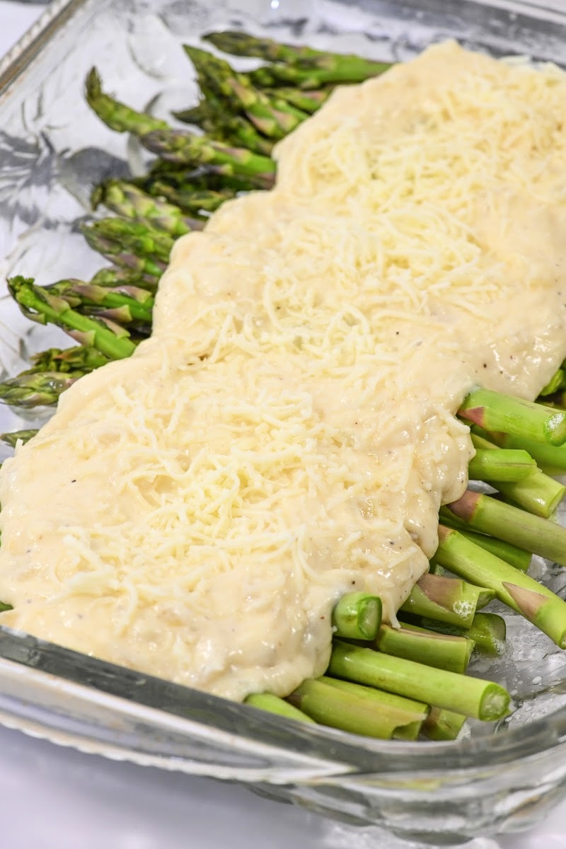 Adding cheese sauce on top of the asparagus