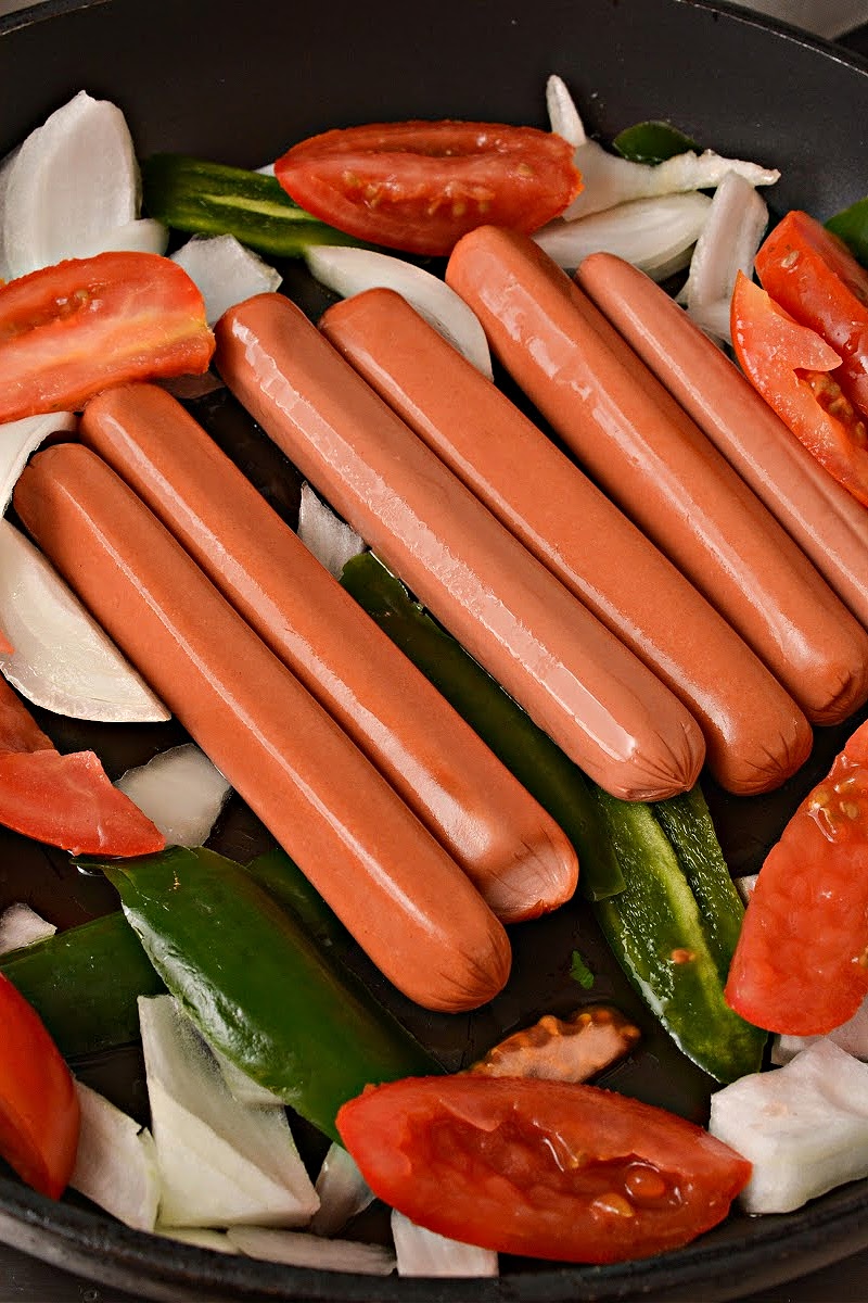 Cooking the hot dogs in the skillet with the veggies
