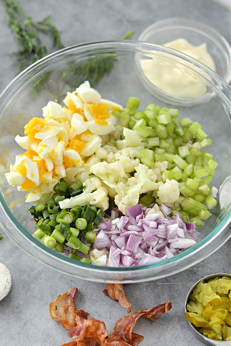 Mixing cauliflower, eggs, and veggies