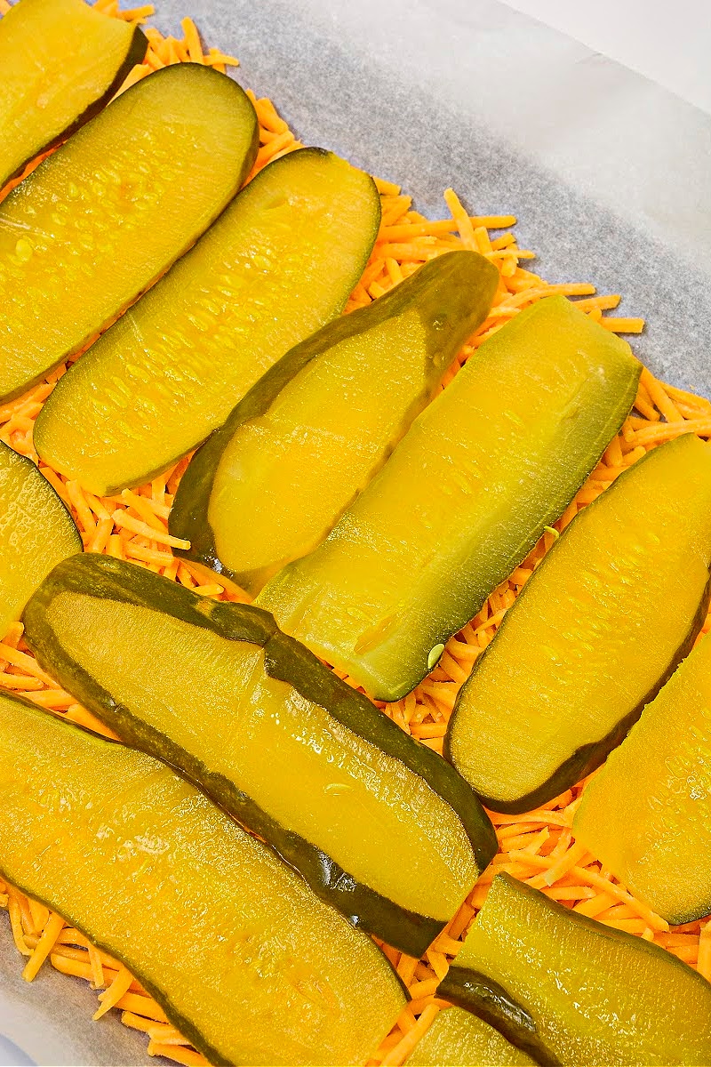 Adding pickles on top of the cheese